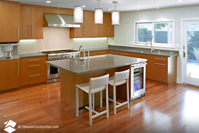 Minimalist medium tone wood floor kitchen photo in Orange County with flat-panel cabinets, light wood cabinets, stainless steel appliances and an island