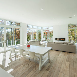 モントリオールの巨大なモダンスタイルのLDKの画像 (白い壁、淡色無垢フローリング、横長型暖炉、漆喰の暖炉まわり)