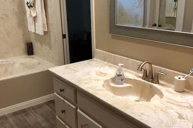 Example of a mid-sized classic 3/4 beige tile and stone slab medium tone wood floor and brown floor bathroom design in Austin with raised-panel cabinets, white cabinets, a two-piece toilet, beige walls, an integrated sink, quartzite countertops and beige countertops