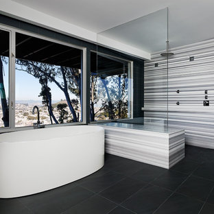Immagine di una stanza da bagno minimalista con doccia a filo pavimento, vasca freestanding e pavimento nero