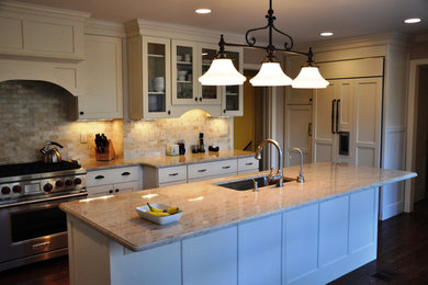 Transitional galley dark wood floor kitchen photo in New York with an undermount sink, shaker cabinets, white cabinets, granite countertops, beige backsplash, stone tile backsplash, stainless steel appliances and an island