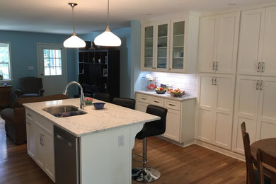 Mid-sized transitional galley medium tone wood floor and brown floor eat-in kitchen photo in Atlanta with an undermount sink, recessed-panel cabinets, white cabinets, quartzite countertops, white backsplash, subway tile backsplash, stainless steel appliances and an island