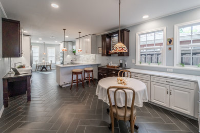 Huge trendy porcelain tile and gray floor eat-in kitchen photo in Dallas with a single-bowl sink, raised-panel cabinets, white cabinets, quartz countertops, gray backsplash, porcelain backsplash, stainless steel appliances, a peninsula and white countertops