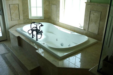 Example of a marble floor bathroom design in Miami with a hot tub and beige walls