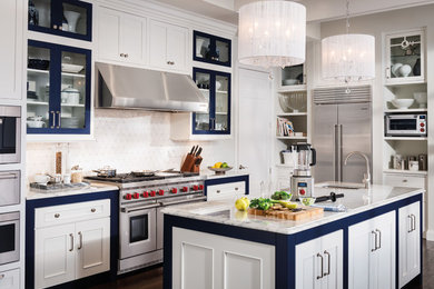 Kitchen - transitional u-shaped kitchen idea in Orange County with stainless steel appliances, an island, recessed-panel cabinets, white cabinets and white backsplash