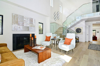 Photo of a mid-sized modern formal open concept living room in Los Angeles with white walls, light hardwood floors, a standard fireplace, a stone fireplace surround, no tv and beige floor.