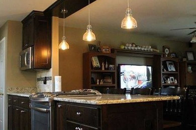 Example of a large classic u-shaped dark wood floor and brown floor enclosed kitchen design in Other with shaker cabinets, dark wood cabinets, granite countertops, stainless steel appliances and a peninsula