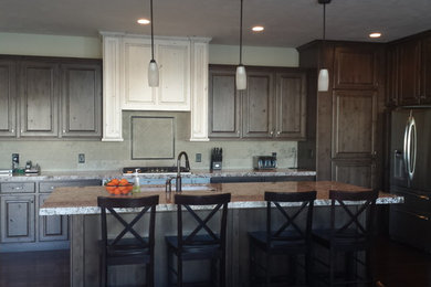 Example of a kitchen design in Salt Lake City with raised-panel cabinets, granite countertops, gray backsplash, stone tile backsplash and stainless steel appliances