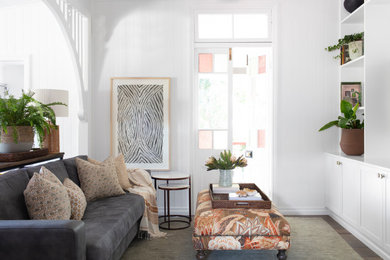 Design ideas for a mid-sized beach style enclosed living room in Brisbane with white walls, medium hardwood floors, a built-in media wall and grey floor.