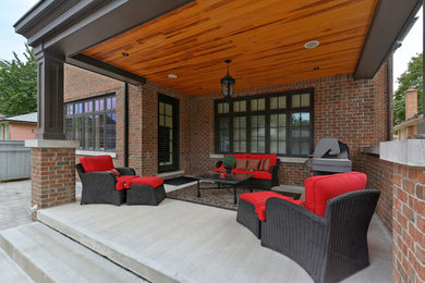 Photo of a large traditional backyard patio in Toronto with concrete pavers and a roof extension.
