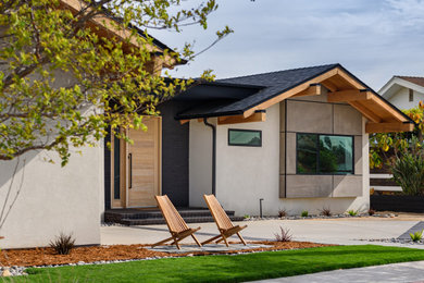Example of a 1950s white one-story stucco exterior home design in San Diego with a shingle roof and a black roof