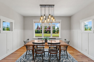 Example of a mid-sized 1960s light wood floor, brown floor, tray ceiling and wainscoting enclosed dining room design in DC Metro with gray walls