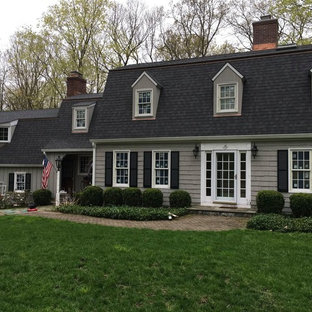Inredning av ett klassiskt stort grått hus, med två våningar, mansardtak och tak i shingel
