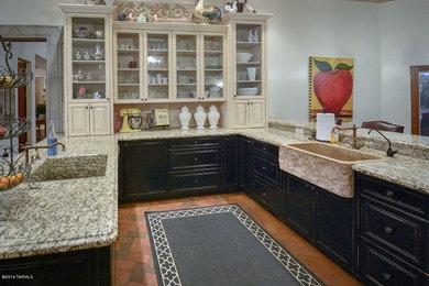 Example of a large country u-shaped brick floor eat-in kitchen design in Phoenix with a farmhouse sink, recessed-panel cabinets, black cabinets, granite countertops and no island