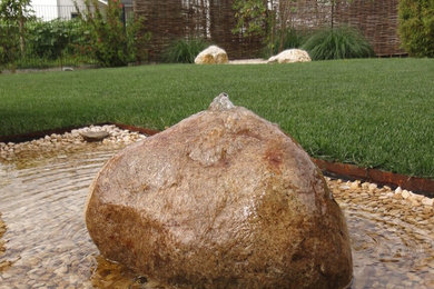 Mittelgroßer Mediterraner Garten hinter dem Haus mit Wasserspiel und Natursteinplatten in München