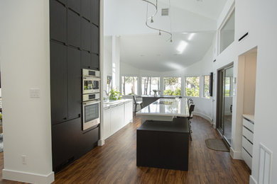 Large trendy medium tone wood floor kitchen photo in Houston with white cabinets, quartz countertops, paneled appliances, an island and white countertops