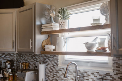 Mid-sized transitional l-shaped medium tone wood floor and brown floor eat-in kitchen photo in Columbus with a farmhouse sink, shaker cabinets, white cabinets, solid surface countertops, gray backsplash, matchstick tile backsplash, stainless steel appliances and no island