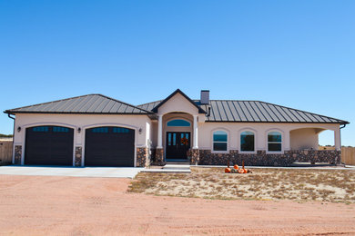 Inspiration for a mid-sized timeless multicolored one-story stucco house exterior remodel in Other with a hip roof and a metal roof