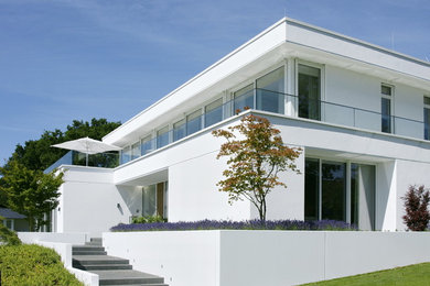 Geräumiges, Zweistöckiges Modernes Einfamilienhaus mit Putzfassade, weißer Fassadenfarbe und Flachdach in Berlin