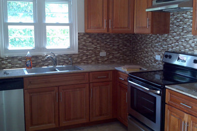 Eat-in kitchen - mid-sized traditional l-shaped porcelain tile and beige floor eat-in kitchen idea in Other with a drop-in sink, raised-panel cabinets, brown cabinets, granite countertops, gray backsplash, mosaic tile backsplash, stainless steel appliances, no island and gray countertops