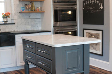 This is an example of a mid-sized eclectic l-shaped separate kitchen in Philadelphia with cork floors, a farmhouse sink, raised-panel cabinets, white cabinets, quartzite benchtops, grey splashback, stone tile splashback, stainless steel appliances, with island, brown floor and white benchtop.