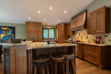 Large arts and crafts u-shaped dark wood floor and brown floor eat-in kitchen photo in Calgary with a farmhouse sink, recessed-panel cabinets, medium tone wood cabinets, granite countertops, beige backsplash, ceramic backsplash, paneled appliances, an island and brown countertops