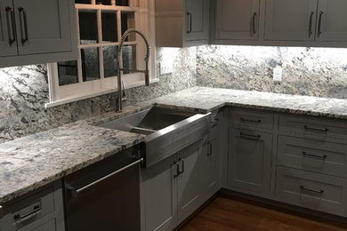 Kitchen - mid-sized transitional dark wood floor and brown floor kitchen idea in San Diego with a farmhouse sink, shaker cabinets, gray cabinets, granite countertops, gray backsplash, stone slab backsplash, stainless steel appliances and an island