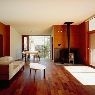 Ispirazione per un piccolo soggiorno moderno aperto con pareti marroni, parquet scuro, stufa a legna, cornice del camino in cemento, nessuna TV e pavimento marrone