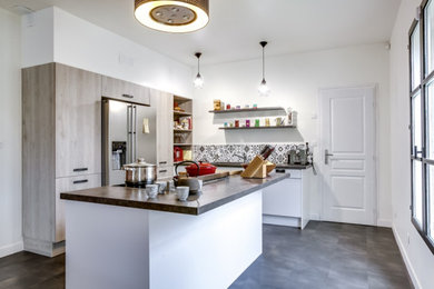 Modern l-shaped open plan kitchen in Paris with an undermount sink, flat-panel cabinets, light wood cabinets, quartzite benchtops, grey splashback, ceramic splashback, stainless steel appliances, ceramic floors, with island, grey floor, brown benchtop and recessed.