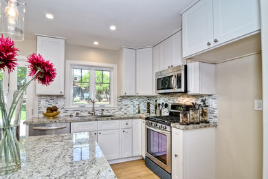 Example of a mid-sized minimalist l-shaped medium tone wood floor open concept kitchen design in Boise with an undermount sink, recessed-panel cabinets, white cabinets, marble countertops, gray backsplash, matchstick tile backsplash, stainless steel appliances and an island