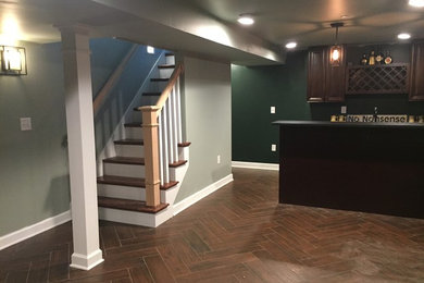 Design ideas for a mid-sized country fully buried basement in Indianapolis with green walls, porcelain floors and brown floor.