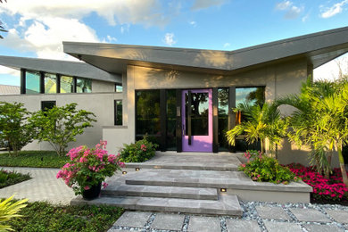 Mid-sized 1950s gray one-story stucco house exterior photo in Other with a butterfly roof, a mixed material roof and a gray roof