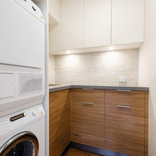 Inspiration for a small contemporary u-shaped utility room in Melbourne with flat-panel cabinets, medium wood cabinets, engineered stone countertops, beige walls, plywood flooring, a stacked washer and dryer and a submerged sink.