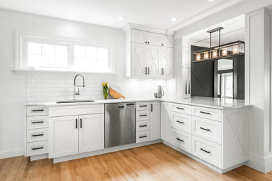 Design ideas for a mid-sized traditional u-shaped eat-in kitchen in Vancouver with an undermount sink, shaker cabinets, white cabinets, quartz benchtops, white splashback, subway tile splashback, stainless steel appliances, medium hardwood floors and a peninsula.
