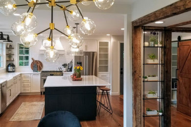 Example of a large farmhouse l-shaped medium tone wood floor, brown floor and exposed beam eat-in kitchen design in New York with a farmhouse sink, shaker cabinets, white cabinets, marble countertops, yellow backsplash, ceramic backsplash, stainless steel appliances, an island and white countertops