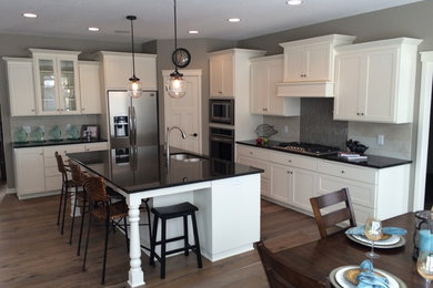 Inspiration for a mid-sized transitional l-shaped dark wood floor open concept kitchen remodel in Minneapolis with a double-bowl sink, shaker cabinets, white cabinets, granite countertops, gray backsplash, ceramic backsplash, stainless steel appliances and an island
