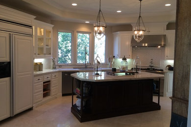 Example of a transitional eat-in kitchen design in Orange County with raised-panel cabinets, white cabinets, white backsplash and an island