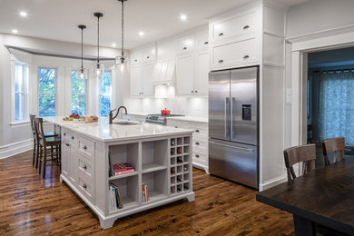 Eat-in kitchen - large traditional single-wall dark wood floor and brown floor eat-in kitchen idea in Ottawa with an undermount sink, shaker cabinets, white cabinets, quartzite countertops, white backsplash, ceramic backsplash, stainless steel appliances and an island