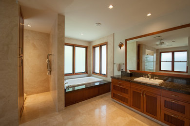 Huge master travertine floor drop-in bathtub photo in Hawaii with a drop-in sink, raised-panel cabinets and marble countertops