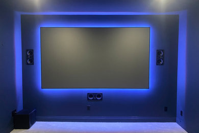 Imagen de cine en casa cerrado moderno de tamaño medio con paredes negras, moqueta, pantalla de proyección y suelo beige