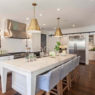 Foto de cocina tradicional renovada con fregadero de doble seno, armarios con paneles empotrados, puertas de armario blancas, encimera de acrílico, salpicadero blanco, salpicadero de azulejos tipo metro, electrodomésticos de acero inoxidable, una isla y suelo de madera oscura