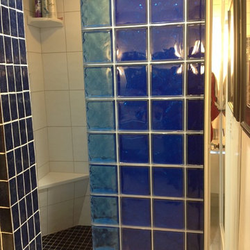 Multi colored glass block shower wall with Wedi corner bench seat in a condo bat