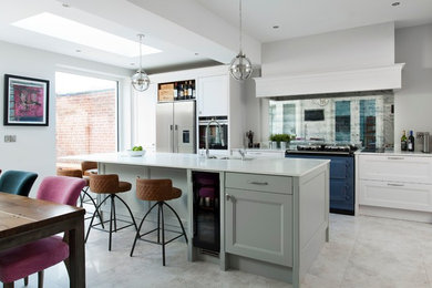 Photo of a mid-sized transitional eat-in kitchen in Belfast with with island, a double-bowl sink, recessed-panel cabinets, white cabinets, mirror splashback, coloured appliances and white floor.