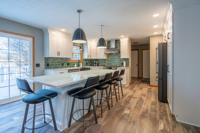 Eat-in kitchen - mid-sized transitional l-shaped vinyl floor and brown floor eat-in kitchen idea in Cleveland with an undermount sink, shaker cabinets, white cabinets, quartz countertops, green backsplash, porcelain backsplash, stainless steel appliances, an island and white countertops