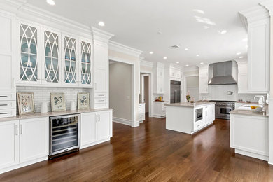 Large transitional dark wood floor kitchen pantry photo in New York with shaker cabinets, white cabinets, quartz countertops, white backsplash, ceramic backsplash, stainless steel appliances and an island