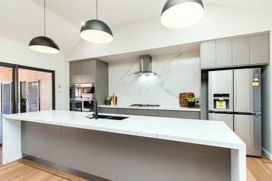 Inspiration for a small modern galley open plan kitchen in Perth with quartz benchtops, white splashback, stone slab splashback, with island and white benchtop.