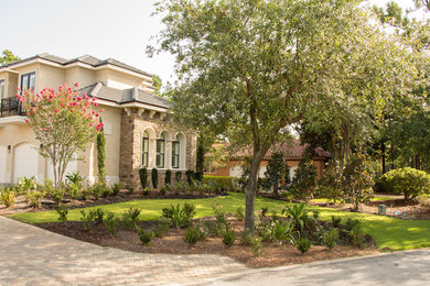 Photo of a large mediterranean front yard partial sun driveway in Miami with brick pavers.