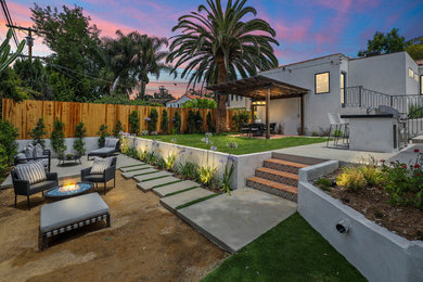 This is an example of a mid-sized transitional backyard concrete paver and wood fence landscaping in Los Angeles with a fire pit.