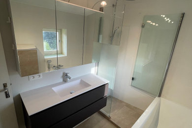 This is an example of a medium sized traditional shower room bathroom in Lyon with glass-front cabinets, black cabinets, a corner bath, a corner shower, a wall mounted toilet, white tiles, ceramic tiles, white walls, ceramic flooring, an integrated sink, beige floors, an open shower, white worktops, a single sink and a floating vanity unit.
