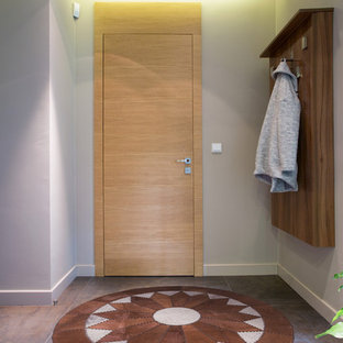 Aménagement d'une porte d'entrée sud-ouest américain de taille moyenne avec un mur gris, un sol en carrelage de porcelaine, une porte simple, une porte en bois clair et un sol marron.